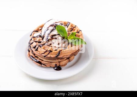 Stapel belgischer Schokoladenwaffeln mit Eis und schokoladenbelag. Frühstückswaffeln mit Eis, Schokoladensoße und Pfefferminze Stockfoto