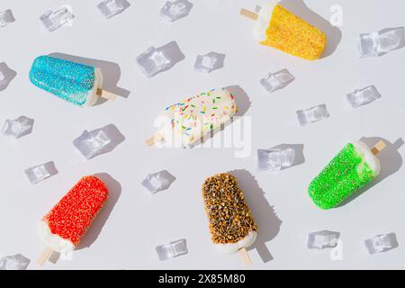 Komposition im Sommermuster mit bunten Eiskrem und Eiswürfeln auf weißem Hintergrund. Minimales kreatives Sommerkonzept. Stockfoto