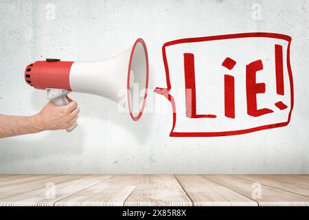 Die Hand des Mannes hält rot-weißes Megaphon an der grungy weißen Wand Stockfoto