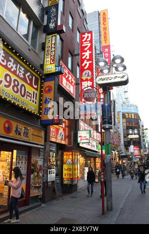 Shibuya, Tokio, Japan, 17. Februar 2016: Vertikale Aufnahme von hell beleuchteten Neonwerbetafeln in Shibuya am frühen Abend im Winter. Stockfoto