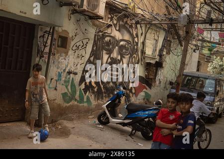 Beirut, Libanon. Mai 2024. Kinder spielen am 18. Mai 2024 in der Nähe eines Wandgemäldes, das den verstorbenen palästinensischen Führer Jassir Arafat im Flüchtlingslager Bourj el-Brajneh in Beirut, Libanon, darstellt. Etwa 25.000 Palästinenser leben in Bourj el-Brajneh. (Foto: Collin Mayfield/SIPA USA) Credit: SIPA USA/Alamy Live News Stockfoto