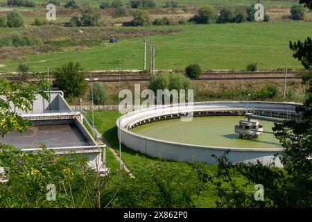 Aus der Vogelperspektive einer Wasseraufbereitungsanlage mit kreisförmigen und rechteckigen Tanks in einer ländlichen Landschaft, umgeben von Grün. Stockfoto