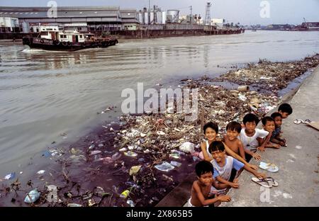Philippinen, Manila, Kinder hängen auf einer Müllhalde ab, die in einem verschmutzten Fluss schwimmt. Stockfoto