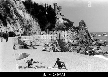 Badegäste am letzten Stück der Strandpromenade von Lloret de Mar, links hinten das Schloss von Lloret de Mar, das in den 1930ern und 1940ern als Strandhaus erbaut wurde, Katalonien 1957. Badende auf dem letzten Abschnitt der Strandpromenade in Lloret de Mar, mit der Burg von Lloret de Mar, die in den 1930er und 1940er Jahren als Strandhaus erbaut wurde, im Hintergrund links, Katalonien 1957. Stockfoto
