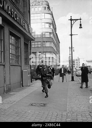 Zwei laufende Soldaten der US-Armee, im Hintergrund ein vermeintlich kriegsverletzter ehem. Wehrmachtssoldat auf Krücken, Berlin 1961. - Original Bildbeschreibung: "Sie haben Stellung bezogen" - die drei in Westberlin stationierten alliierten Schutzmächte. An den Grenzen unserer Inselstadt sind die feldmäßig ausgerichteten Truppen in Stellung gegangen, um die Freiheit Berlins und damit die Freiheit der ganzen Welt zu verteidigen. - U.B.z.: Amerikaner in der Kochstraße Stockfoto