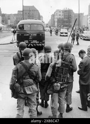 Soldaten der US-Army stehen mit geschulterten Gewehren und einem Emfangsgerät am Checkpoint Charlie, Berlin 1961. - Originale Bildbeschreibung: 'Gestern Zwischenfall an der Sektorengrenze Friedrichstr. Vopos wollten drei amerik. Busse nicht nach Ost-Berlin lassen - drei amerikanische Busse trafen gestern gegen 14 Uhr 30 am Sektorenübergang Friedrichstr. ein- Da es die Amerikaner ablehnten sich von den Vopos kontrollieren zu lassen, wurde die Durchfahrt vorerst verweigert. Ein amerikanischer Oberst protestierte daraufhin bei den Sowjets, worauf die Busse unkontrolliert nach spannenden zwei Stun Stockfoto