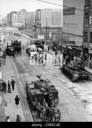 Reger Trubel und diverse Fahrzeuge am Checkpoint Charlie, Berlin 1961. - Originale Bildbeschreibung: "Übergriffe werden abgewiesen - zu einem schweren Grenzzwischenfall, kam es auch heute wieder an der Friedrich-/Ecke Kochstraße, als zwei amerikanische Reiseomnibussen die Einfahrt in den sowjetisch-besetzten Sektor verboten werden sollte. Englische und amerikanische Panzertruppeneinheiten bezogen Stellung, um international festgelegte Rechte der vier Besatzungsbehörden zu wahren." Stockfoto