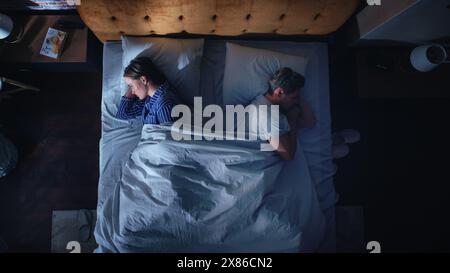 Top View Apartment Schlafzimmer: Streitendes junges Paar im Bett in der Nacht. Junge Leute nach einem Kampf wenden sich von jedem ab. Familie von zwei in einem Streit. Missbrauch, Häusliche Gewalt, Entfremdung. Von Oben Nach Unten Stockfoto