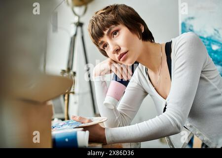 Eine Frau mit Hand am Kinn sitzt an einem Schreibtisch. Stockfoto