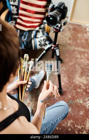 Eine Frau, die auf dem Boden saß, in Malerei mit einem lebhaften Pinsel getaucht. Stockfoto