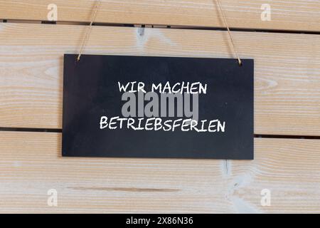 Symbolbild der Firmenfeiertage: Auf einem Holzbrett mit der deutschen Aufschrift uns MACHEN BETRIEBSFERIEN Wir sind auf Firmenfeiertage *** Symbolbild der Firmenfeiertage auf einem Holzbrett mit der deutschen Aufschrift uns MACHEN BETRIEBSFERIEN Wir sind auf Firmenfeiertage Copyright: XUdoxHerrmannx Stockfoto