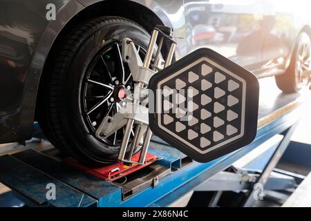 Die Radwuchtmaschine des Autos wird mit einem Laserreflektor kalibriert, der an jedem Reifen angebracht ist, um die mittlere Fahreinstellung einzustellen. Auto im Auto-Service. Auswuchtreifen Radmaschine. Stockfoto