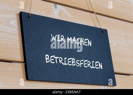 Symbolbild der Firmenfeiertage: Auf einem Holzbrett mit der deutschen Aufschrift uns MACHEN BETRIEBSFERIEN Wir sind auf Firmenfeiertage *** Symbolbild der Firmenfeiertage auf einem Holzbrett mit der deutschen Aufschrift uns MACHEN BETRIEBSFERIEN Wir sind auf Firmenfeiertage Copyright: XUdoxHerrmannx Stockfoto