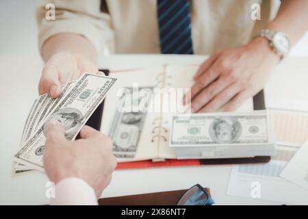 Ein Mann, der Hundert Dollar-Scheine anbietet. Hand eines Geschäftsmannes, der seinem Partner Geld gibt. Hand erhält Geld vom Geschäftsmann. Bestechung, Bestechung, Stockfoto