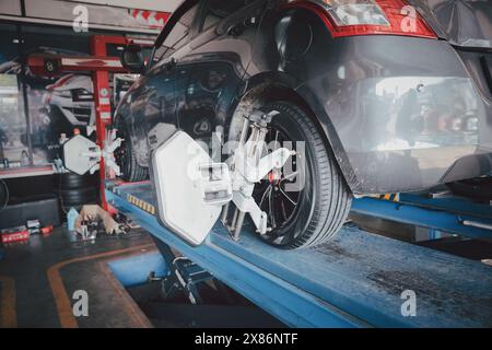 Die Radwuchtmaschine des Autos wird mit einem Laserreflektor kalibriert, der an jedem Reifen angebracht ist, um die mittlere Fahreinstellung einzustellen. Auto im Auto-Service. Auswuchtreifen Radmaschine. Stockfoto