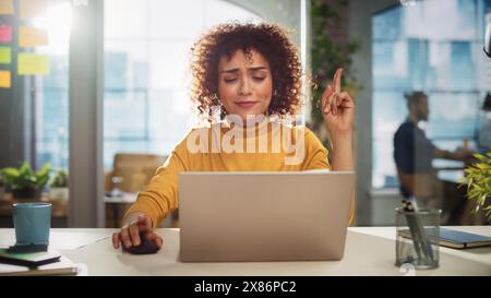Porträt einer attraktiven arabischen Frau, die an einem Schreibtisch in der Kreativagentur sitzt. Junger, stilvoller Manager mit lächelnden lockigen Haaren und einem Idea Manager, der in Modern Company arbeitet. Stockfoto