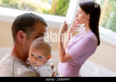 Frau raucht neben neugeborenem Baby Stockfoto