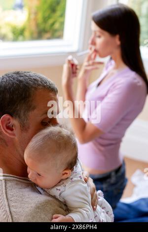 Frau raucht neben neugeborenem Baby Stockfoto