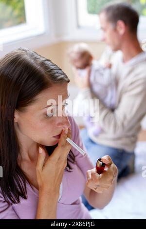 Frau raucht neben neugeborenem Baby Stockfoto