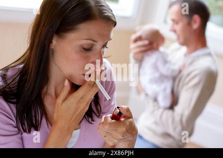 Frau raucht neben neugeborenem Baby Stockfoto