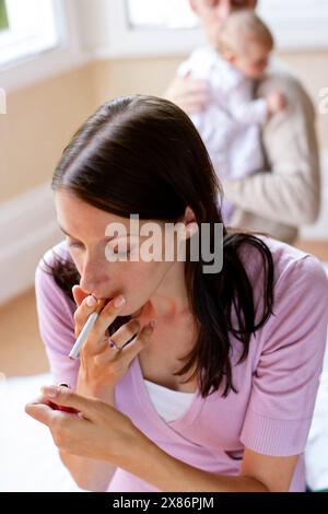 Frau raucht neben neugeborenem Baby Stockfoto