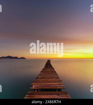 Friedliche Meereslandschaft bei Sonnenaufgang mit einem alten hölzernen Dock, der in das ruhige Meer führt Stockfoto