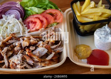 Gyros: Saftige, gewürzte Fleischscheiben, perfekt gegrillt, in eine warme Pita gewickelt, mit frischen Tomaten, Zwiebeln und cremiger Tzatziki-Sauce garniert Stockfoto