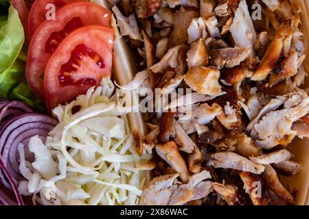 Gyros: Saftige, gewürzte Fleischscheiben, perfekt gegrillt, in eine warme Pita gewickelt, mit frischen Tomaten, Zwiebeln und cremiger Tzatziki-Sauce garniert Stockfoto