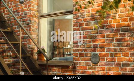 Establishment Shot: Eine Aufnahme eines Fensters eines gemütlichen Brownstone House Apartments, aufgenommen von einer Treppe außerhalb des Hauses. Das Apartment ist kreativ im urbanen Brooklyn-Stil eingerichtet Stockfoto