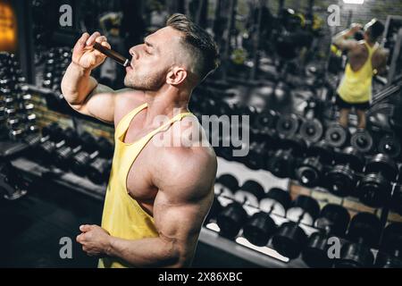 Muskelathlet trinken flüssiges Vitamin b 12 oder Ergänzung in kleiner Einweg-schwarzer Flasche, Bodybuilder-Mann mit Sporternährung in Ampule-Tropfen Stockfoto