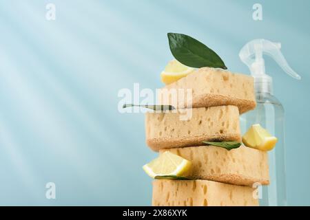 Umweltfreundliche Reinigungswerkzeuge, Haushaltsreinigungsschwämme, Sprühflasche, Zitrone, hölzerne umweltfreundliche Bürsten mit fliegenden grünen Blättern und Bläschen o Stockfoto