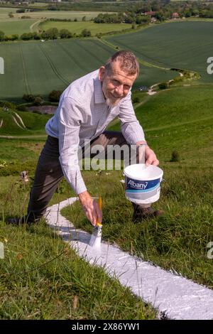 Wilmington, East Sussex, UK, 23.05.2024, Volunteer Nick Brewer aus Wilmington hilft, den langen Mann von Wilmington zu malen. Die Riesenfigur an den steilen Hängen des Windover Hill ist 72 Meter hoch und hält zwei Stangen. Ursprünglich wurde angenommen, dass es sich um ein neolithikum handelt, heute wird angenommen, dass es sich um das 16. Oder 17. Jahrhundert handelt. Die Neumalerei ist das Finale einer Spendenaktion zur Unterstützung der Arbeit der Sussex Archaeology Society (die als Sussex Past gehandelt wird), die die berühmte Hügelfigur „The Guardian of the South Downs“ besitzt und pflegt. Die Kampagne sammelte mehr als £10.000 und fast 300 Spender zahlten £30,00 an A Stockfoto