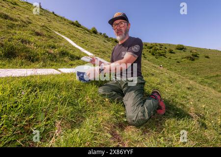 Wilmington, East Sussex, UK, 23.05.2024, Garry Ticehurst, zeigt sein Long-man-Tattoo, während er freiwillig hilft, den Long-Mann von Wilmington zu malen. Die Riesenfigur an den steilen Hängen des Windover Hill ist 72 Meter hoch und hält zwei Stangen. Ursprünglich wurde angenommen, dass es sich um ein neolithikum handelt, heute wird angenommen, dass es sich um das 16. Oder 17. Jahrhundert handelt. Die Neumalerei ist das Finale einer Spendenaktion zur Unterstützung der Arbeit der Sussex Archaeology Society (die als Sussex Past gehandelt wird), die die berühmte Hügelfigur „The Guardian of the South Downs“ besitzt und pflegt. Die Kampagne sammelte mehr als £10.000 und sah fast 3 Stockfoto