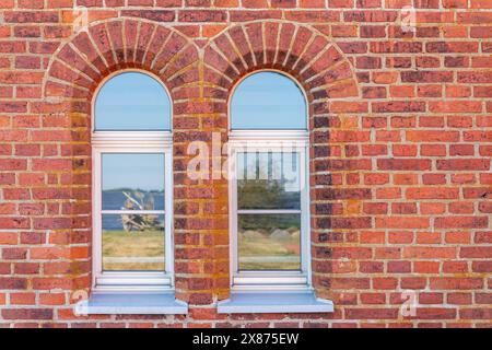 Alte rote Backsteinmauer, Tageslicht, mit zwei Bogenfenstern. Horizontales Foto. Stockfoto