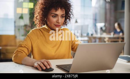 Porträt einer ausdrucksstarken, multiethnischen arabischen Frau, die an einer kreativen Stelle in einem Werbeunternehmen arbeitet. Glücklicher Manager kommuniziert mit Kollegen und schreibt einen Marketingplan. Stockfoto
