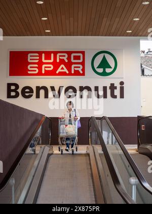 Cremona, Italien - 5. Mai 2024, Käuferinnen stehen auf einer Rolltreppe mit vollem Einkaufswagen am Eingang eines eurospar-Geschäfts und begrüßen Kunden Stockfoto