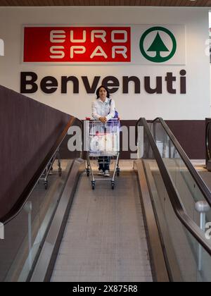 Cremona, Italien - 5. Mai 2024, Käuferinnen stehen auf einer Rolltreppe mit vollem Einkaufswagen am Eingang eines eurospar-Geschäfts und begrüßen Kunden Stockfoto