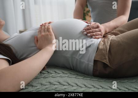 Doula kümmert sich um schwangere Frauen drinnen, Nahaufnahme. Vorbereitung auf die Geburt des Kindes Stockfoto