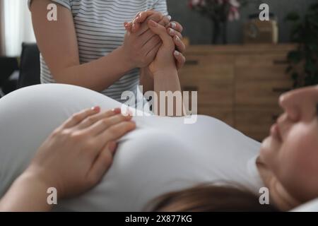 Doula kümmert sich um schwangere Frauen drinnen, Nahaufnahme. Vorbereitung auf die Geburt des Kindes Stockfoto