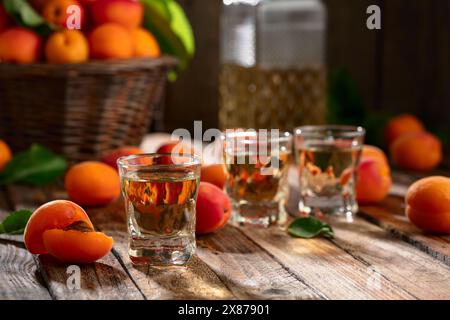 Aprikosenlikör oder Grappa und frische Aprikosen auf einem alten Holztisch. Stockfoto