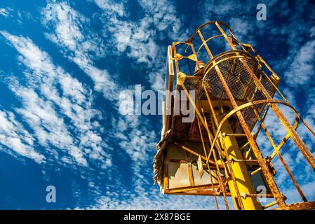 Maritimer Leuchtturm mit gelbem Funksignal, der zur Führung von Schiffen dient, die von der Zeit getragen und verrostet wurden, am blauen Himmel mit weißen Wolken am Hafen von Malamocco Stockfoto