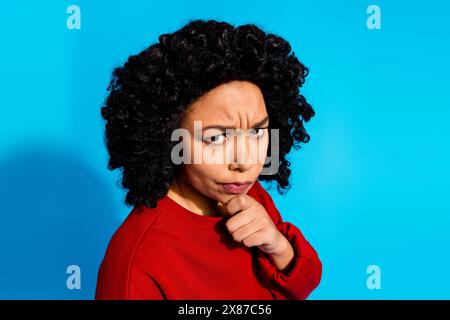 Foto-Porträt der attraktiven jungen Frau stimmungsvoll nachdenklich unzufrieden gekleidete stilvolle rote Kleidung isoliert auf blauem Farbhintergrund Stockfoto