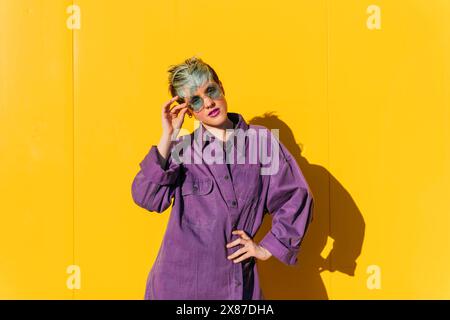 Frau in lila Jacke posiert vor der gelben Wand Stockfoto