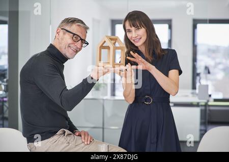 Zwei lächelnde Architekten untersuchen Modellhaus im Büro Stockfoto