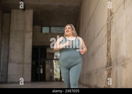 Glückliche kurvige Frau, die an der Wand rannte Stockfoto