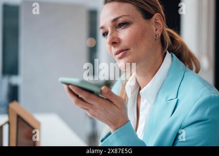 Reifer Architekt spricht im Büro über Smartphone-Lautsprecher Stockfoto