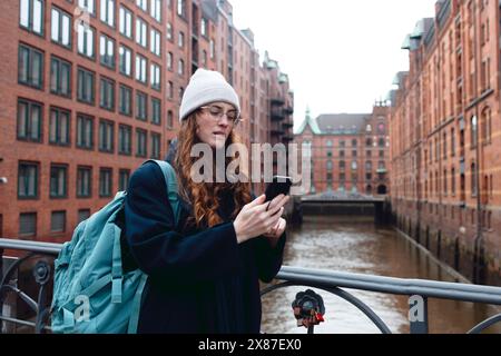 Tourist mit Rucksack mit Smartphone in der Nähe von Gebäuden in der Speicherstadt Stockfoto