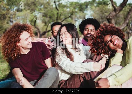 Glückliche multirassische Freunde sitzen zusammen im Park Stockfoto