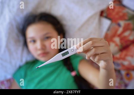 Das kranke Mädchen zeigt die Temperatur auf dem Thermometer zu Hause Stockfoto