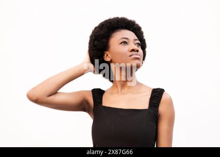 Junge Afro-Frau mit Hand im Haar vor weißem Hintergrund Stockfoto